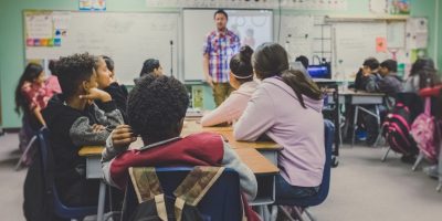 Teacher standing in front of a class of youths.