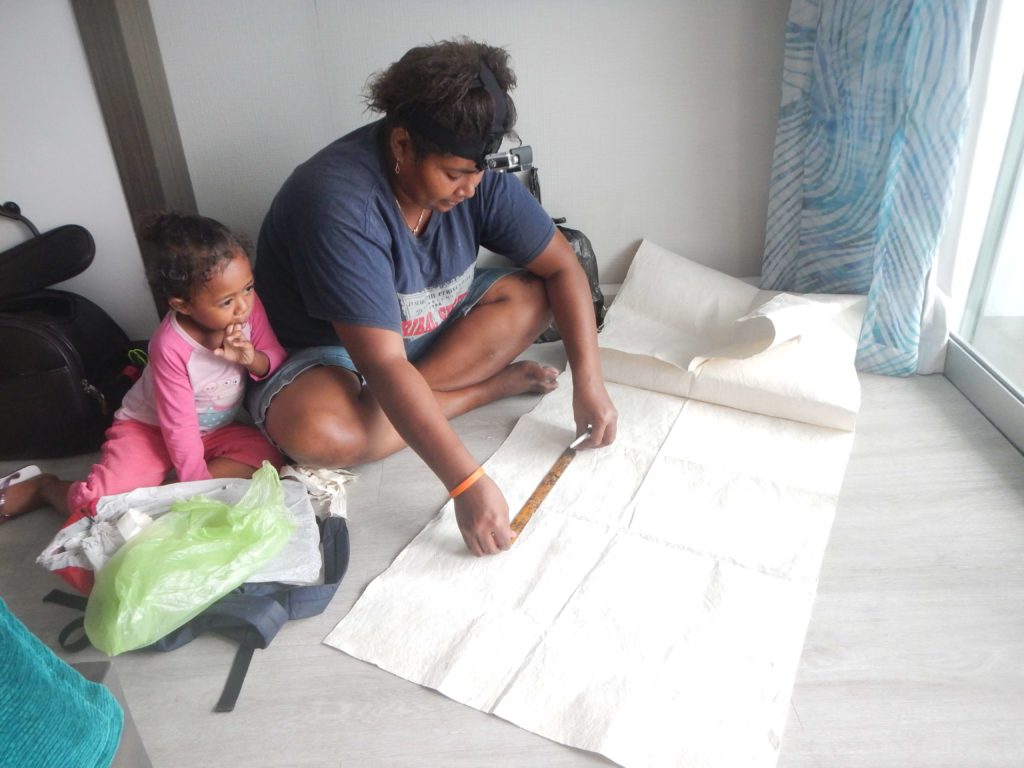 Buna and her daughter preparing to cut tapa sheets for printing